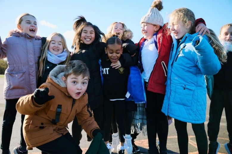 Diverse group of primary age children in coats in the playground