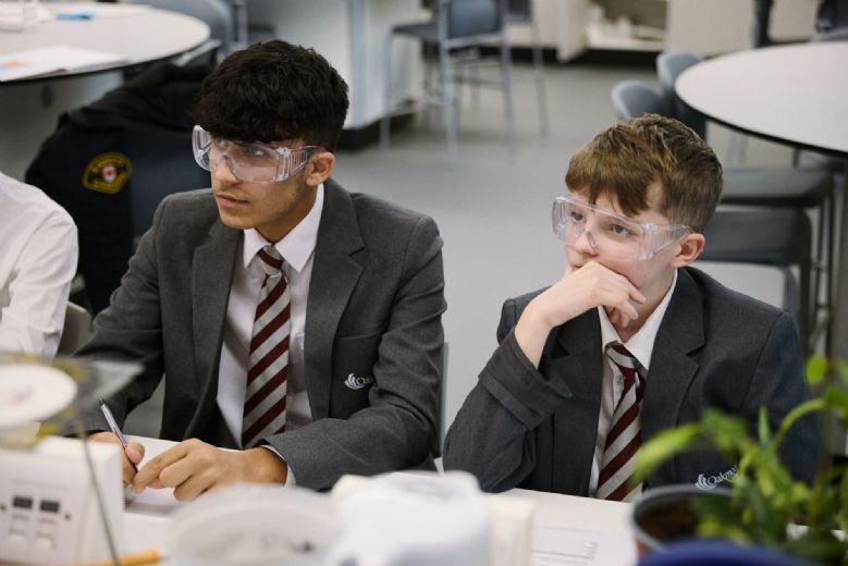 secondary school students in a science lesson, wearing protective goggles